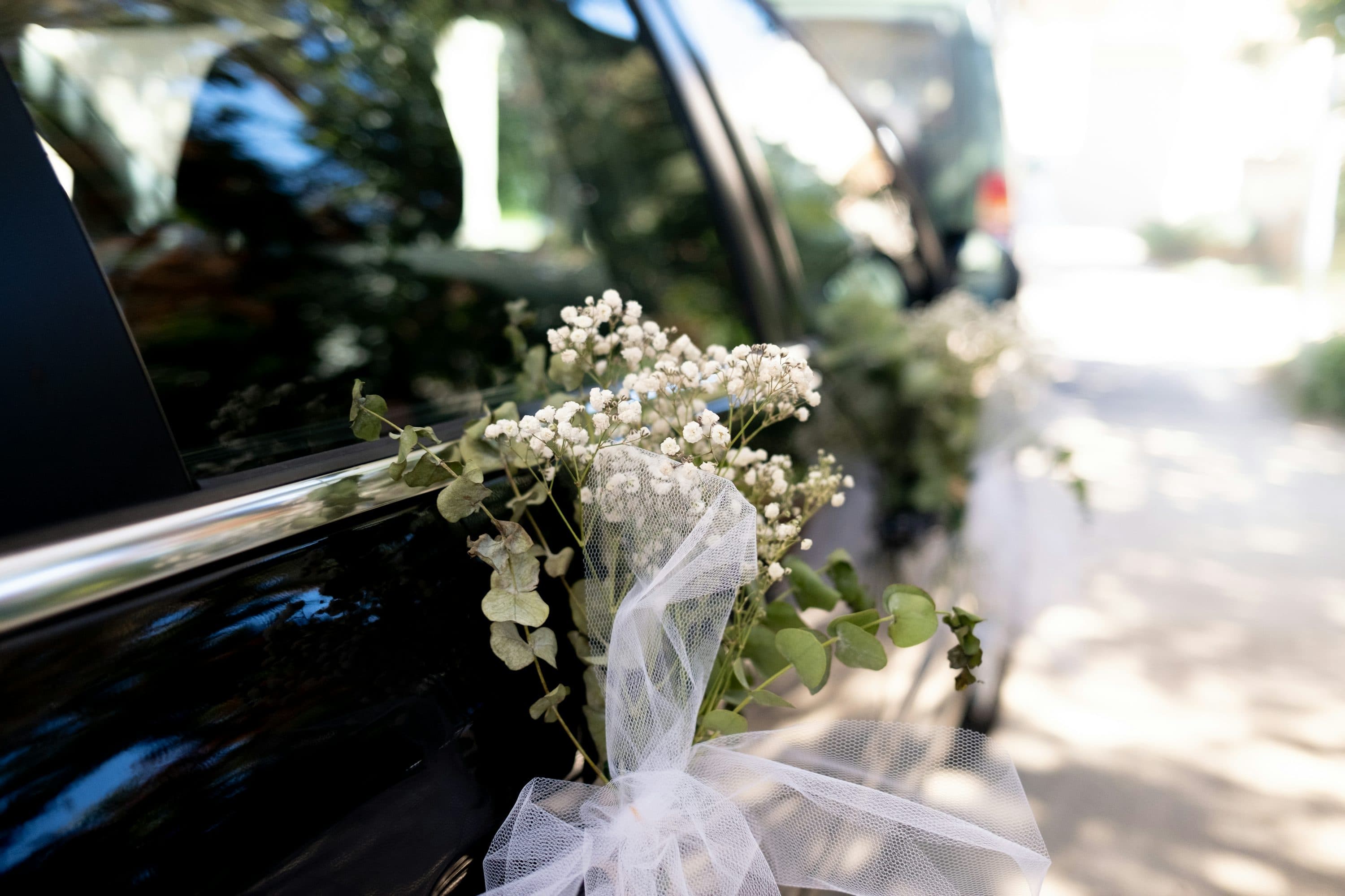 Delicate white flowers and ribbon decorating a wedding car door