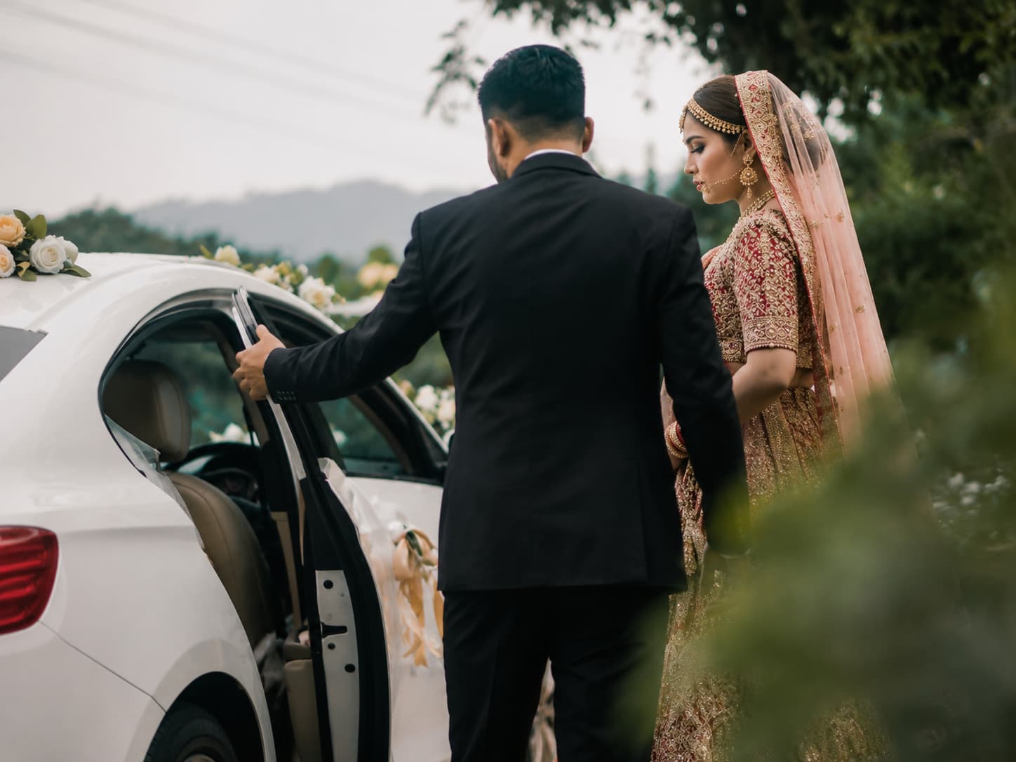 Chauffeur opening a white wedding car door for a bride