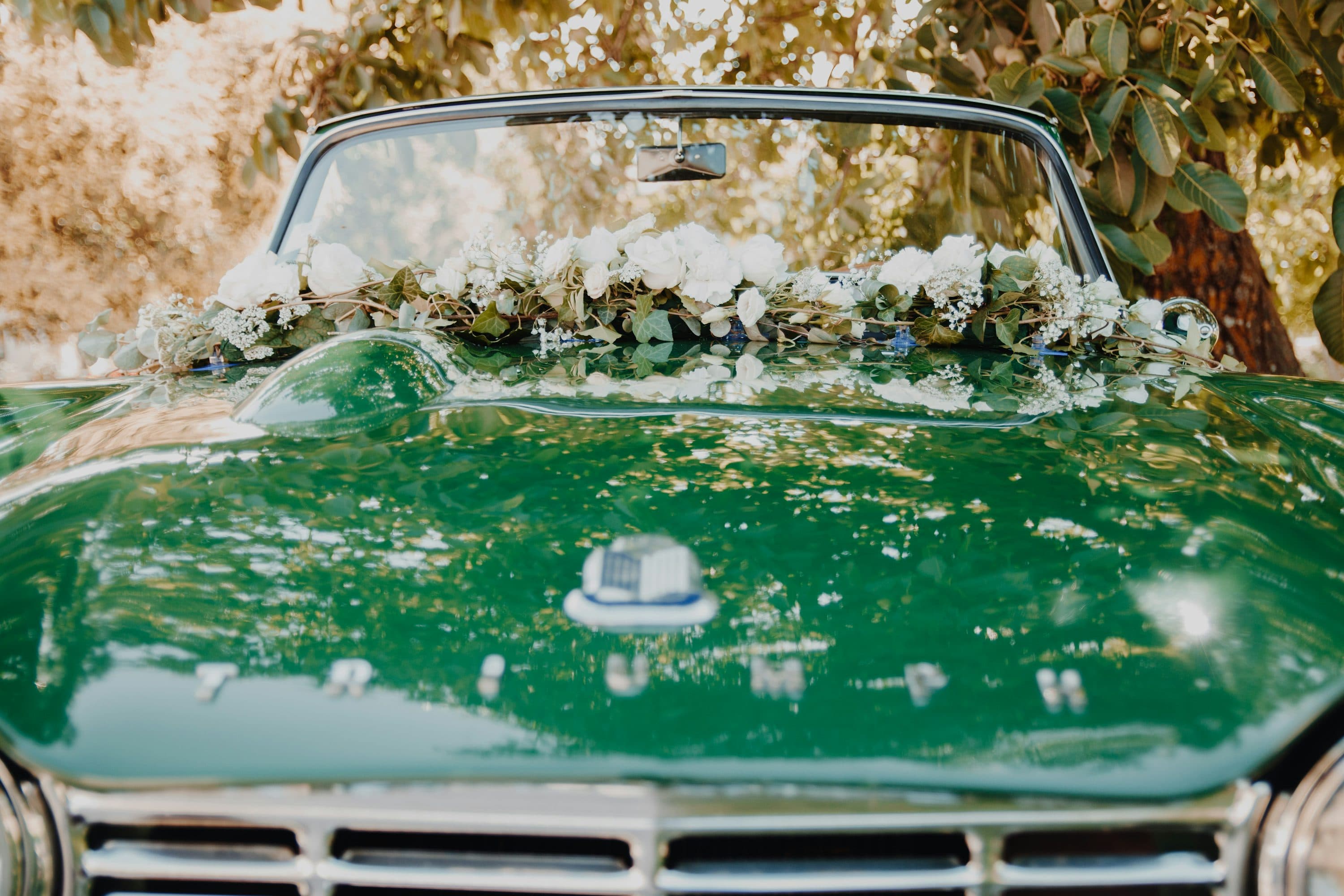 Green vintage wedding car decorated with white flowers