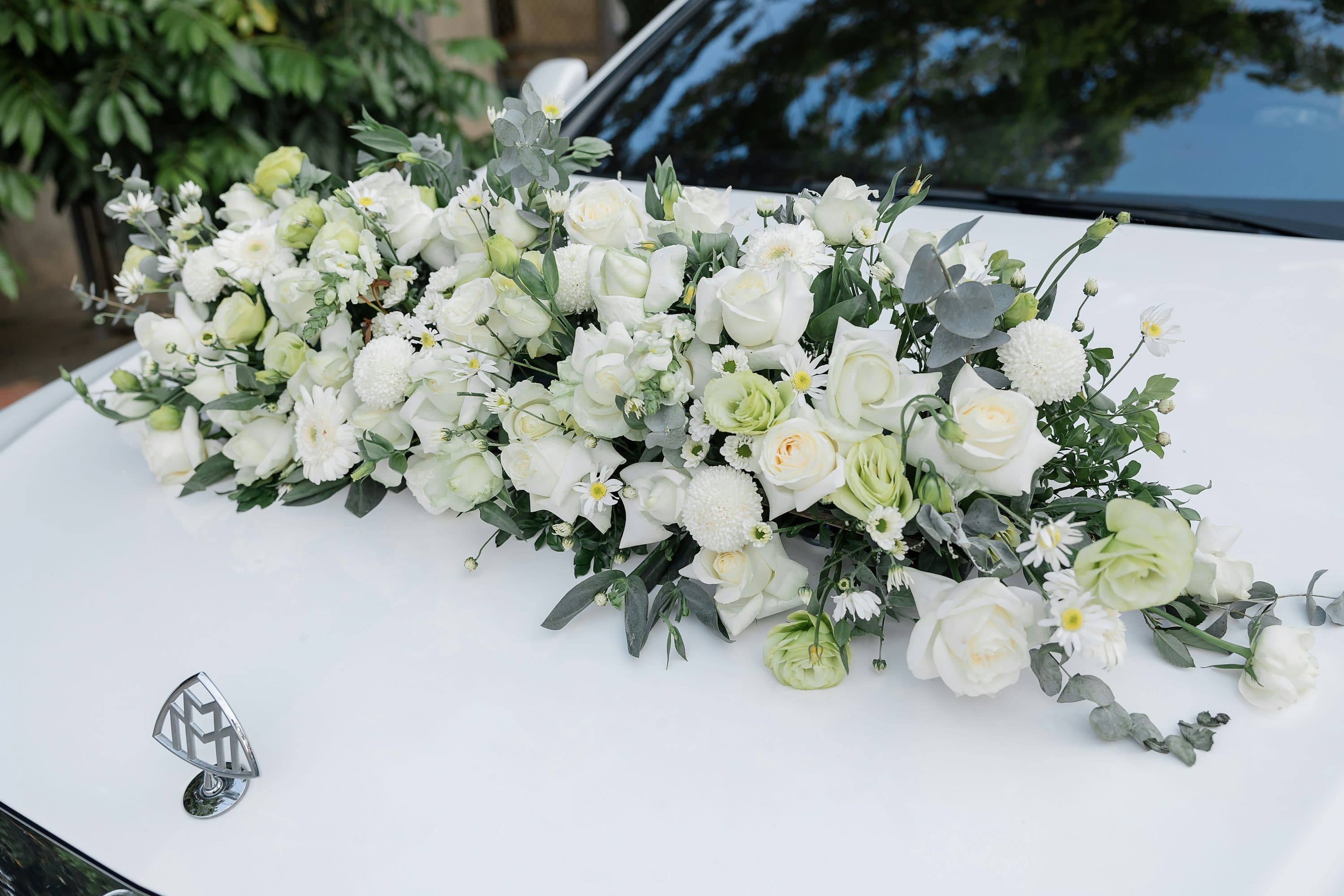 White flowers arranged on the hood of a luxury wedding car